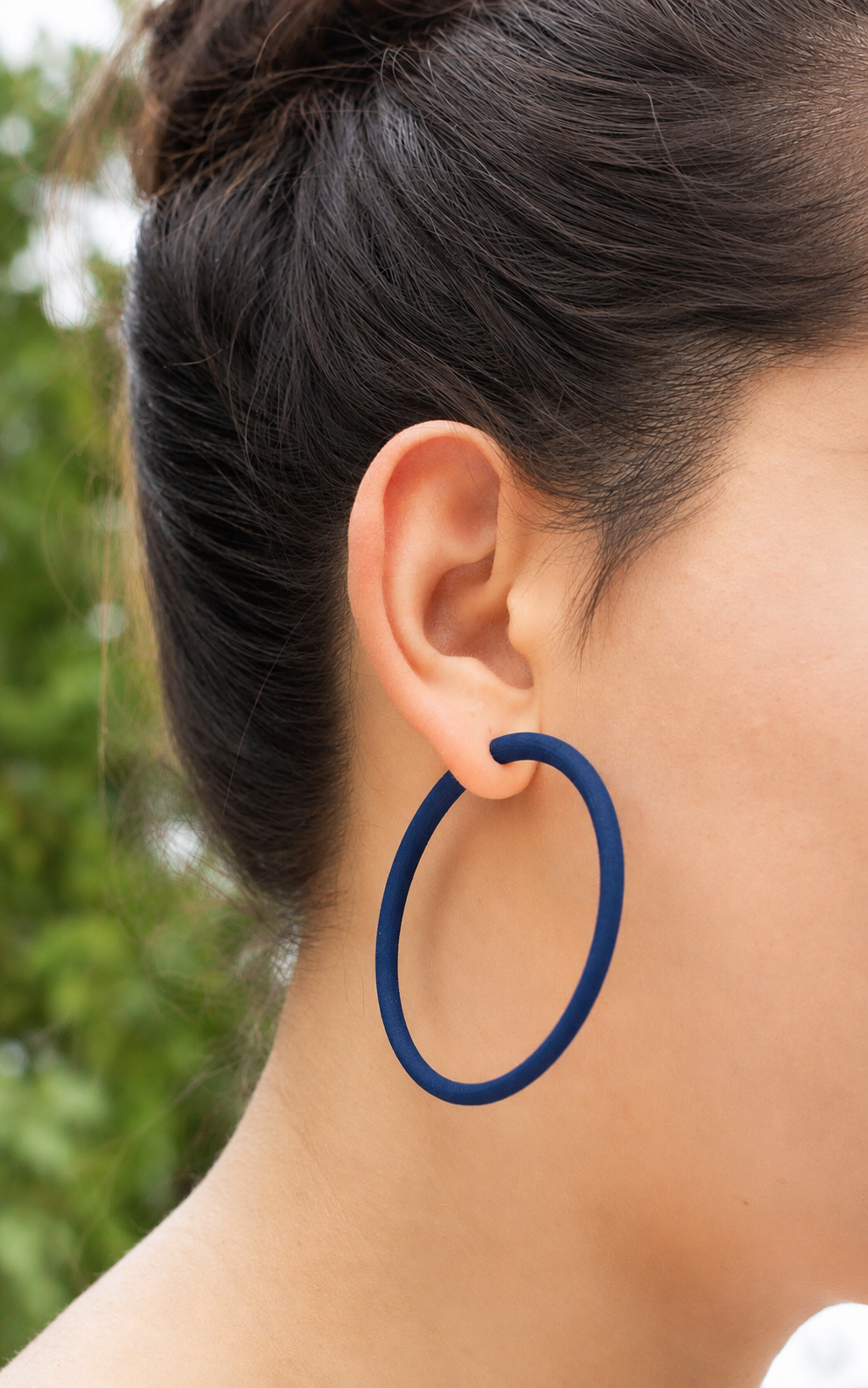 Jeune femme cheveux bruns et anneaux doreilles indigo