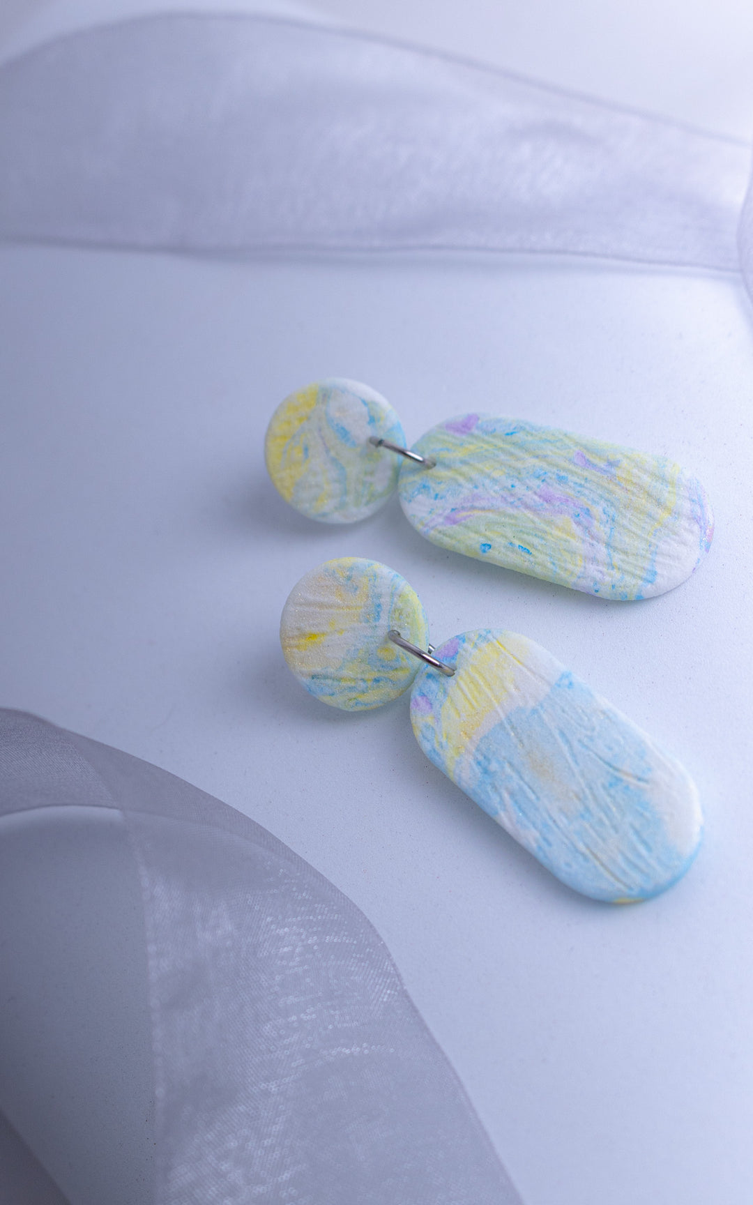 Détail de boucles d’oreilles ultralégères en nylon recyclé imprimé 3D, texture marbrée pastel multicolore, finition artisanale, Vox &amp; Oz