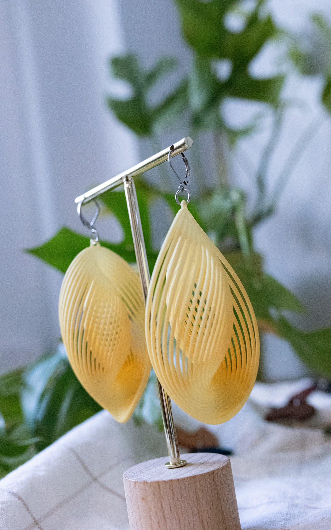 Boucles d’oreilles OASIS jaune pastel ultralégères en nylon recyclé imprimé 3D présentées dans une ambiance végétale signées Vox &amp; Oz
