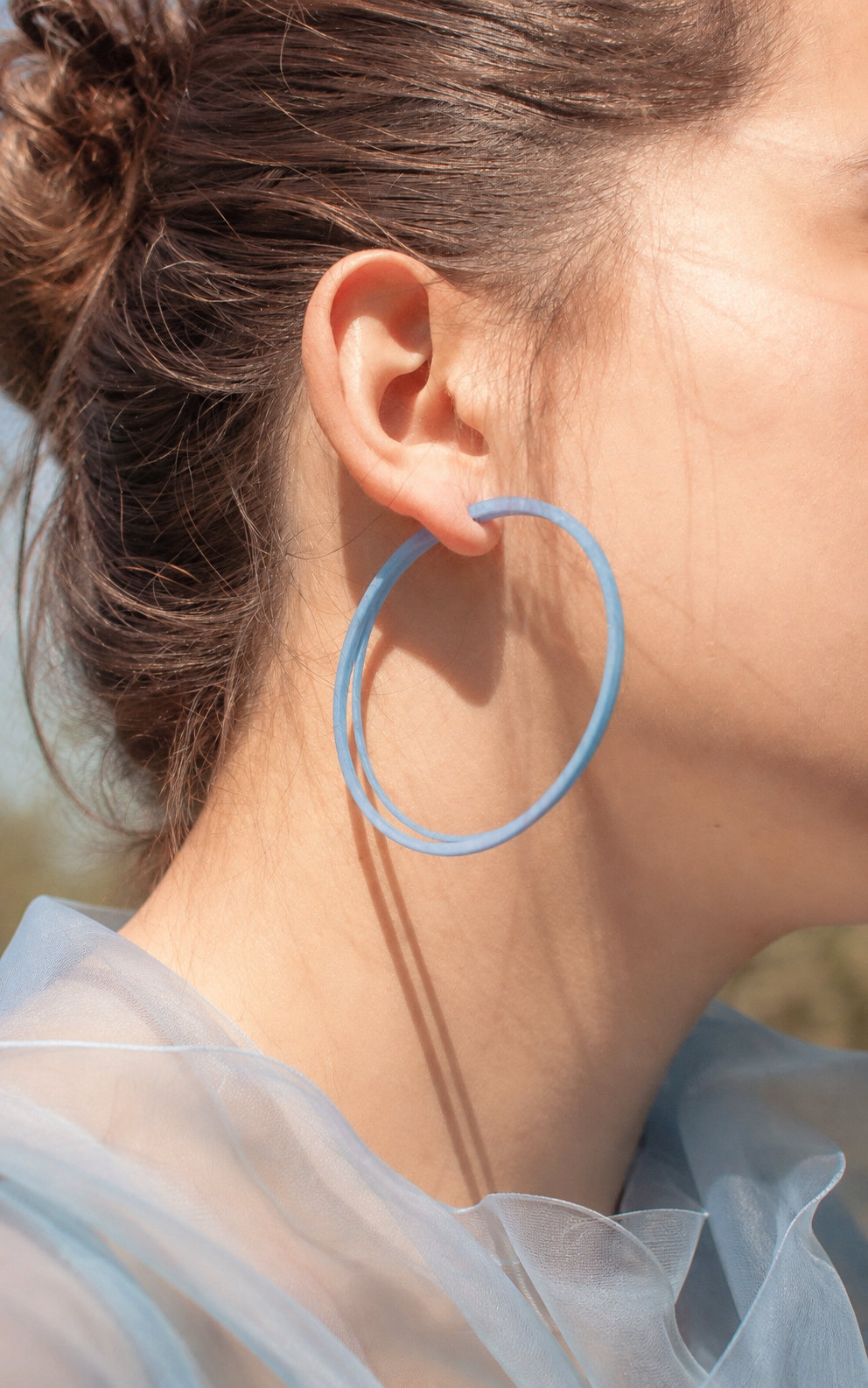 Mannequin portant les boucles d'oreilles SCOOP 7 cm bleu doux en nylon recyclé, grands anneaux ultralégers fabriqués à la main au Québec par Vox & Oz.
