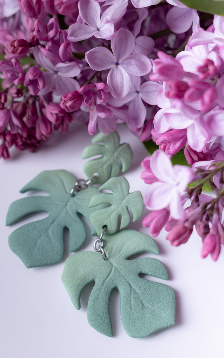 Boucles d’oreilles MAUI Monstera vert sauge dans une ambiance florale lilas