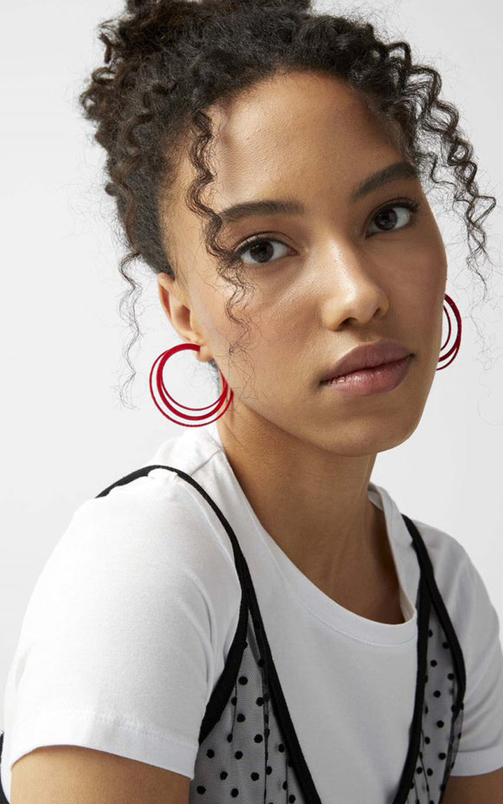 Jeune femme aux cheveux bouclés noirs avec boucles doreilles rouges