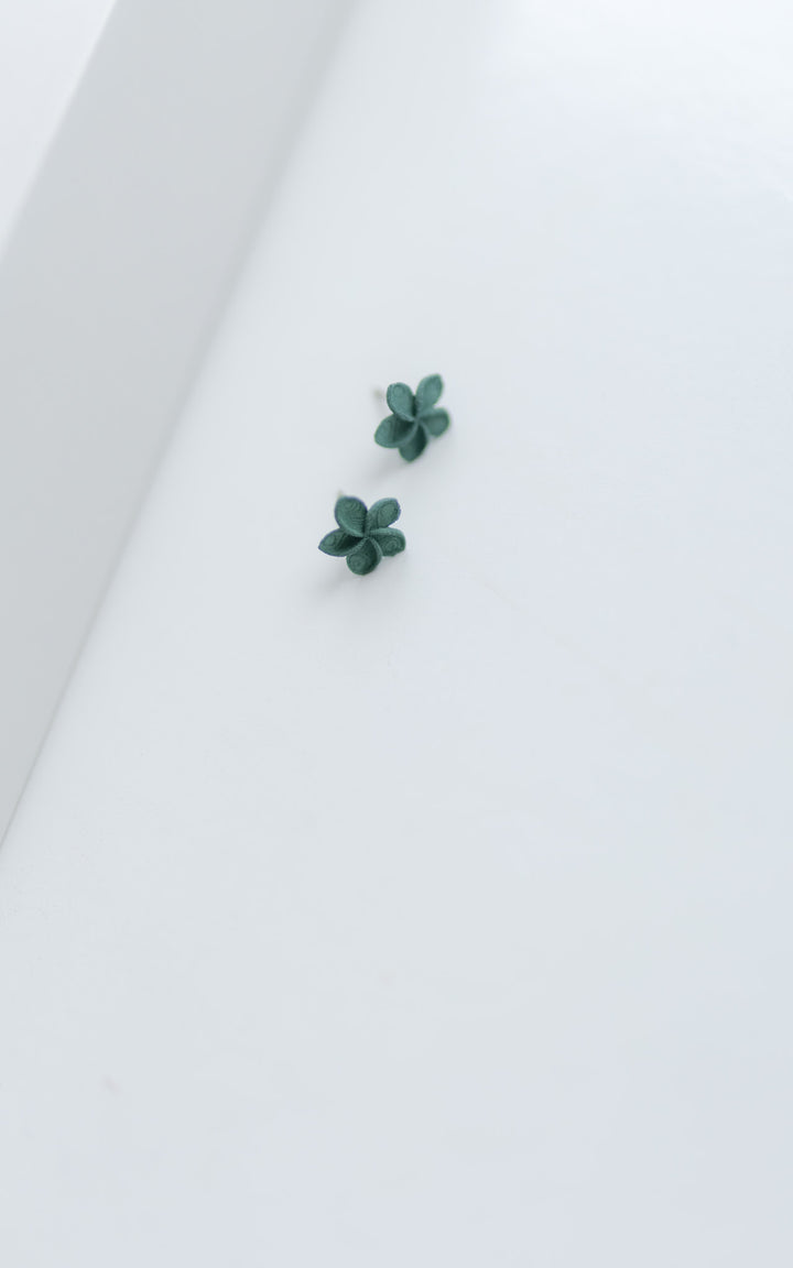 Puces d’oreilles OHANA vertes de Vox & Oz – bijoux floraux 3D en nylon recyclé, posées sur fond blanc
