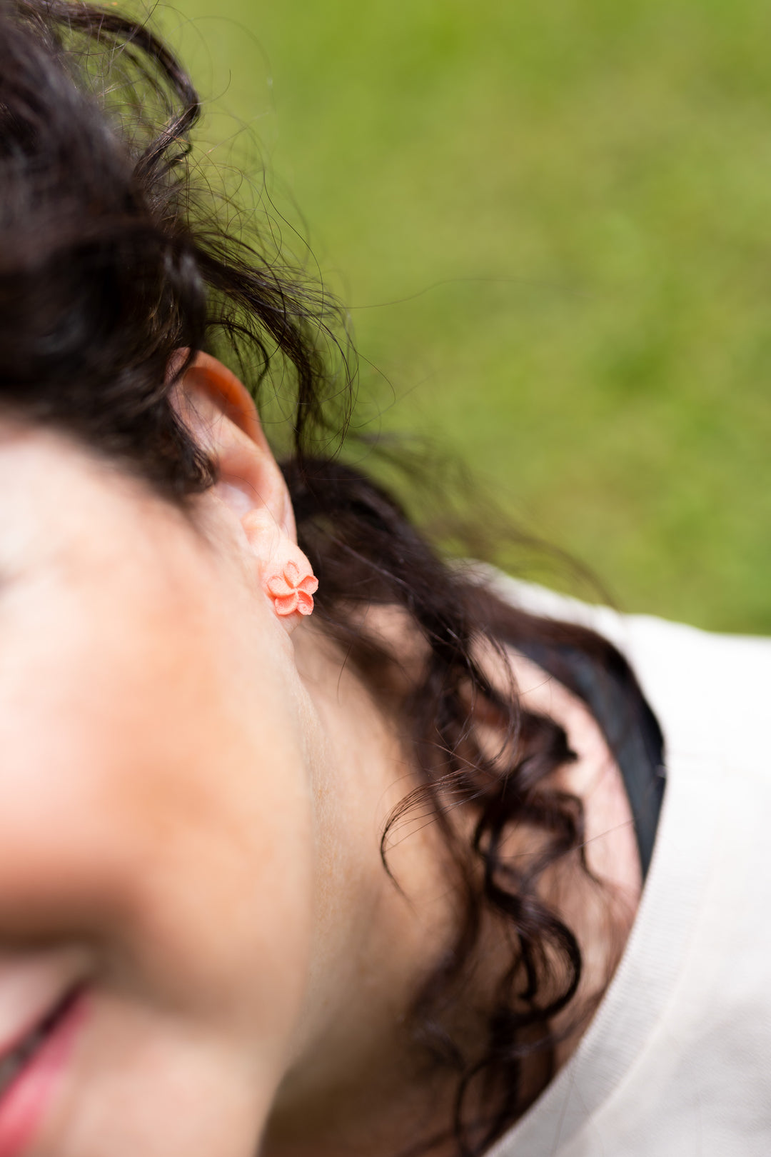 Femme aux cheveux noirs portant les puces OHANA corail de Vox & Oz – boucles d’oreilles fleur de plumeria 3D faites au Québec