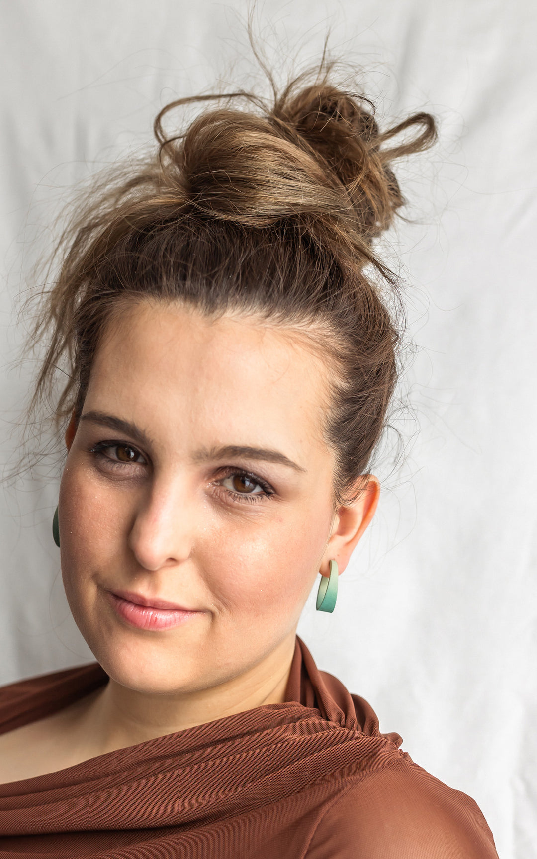 Belle jeune fille avec une chevelure brune, haut chignon.  Boucles d'oreilles aux teintes dégradées de vert. magnifiquement doux, un look des plus attrayant.  Bijoux pour femmes  qui aiment la mode et les nouvelles tendances.