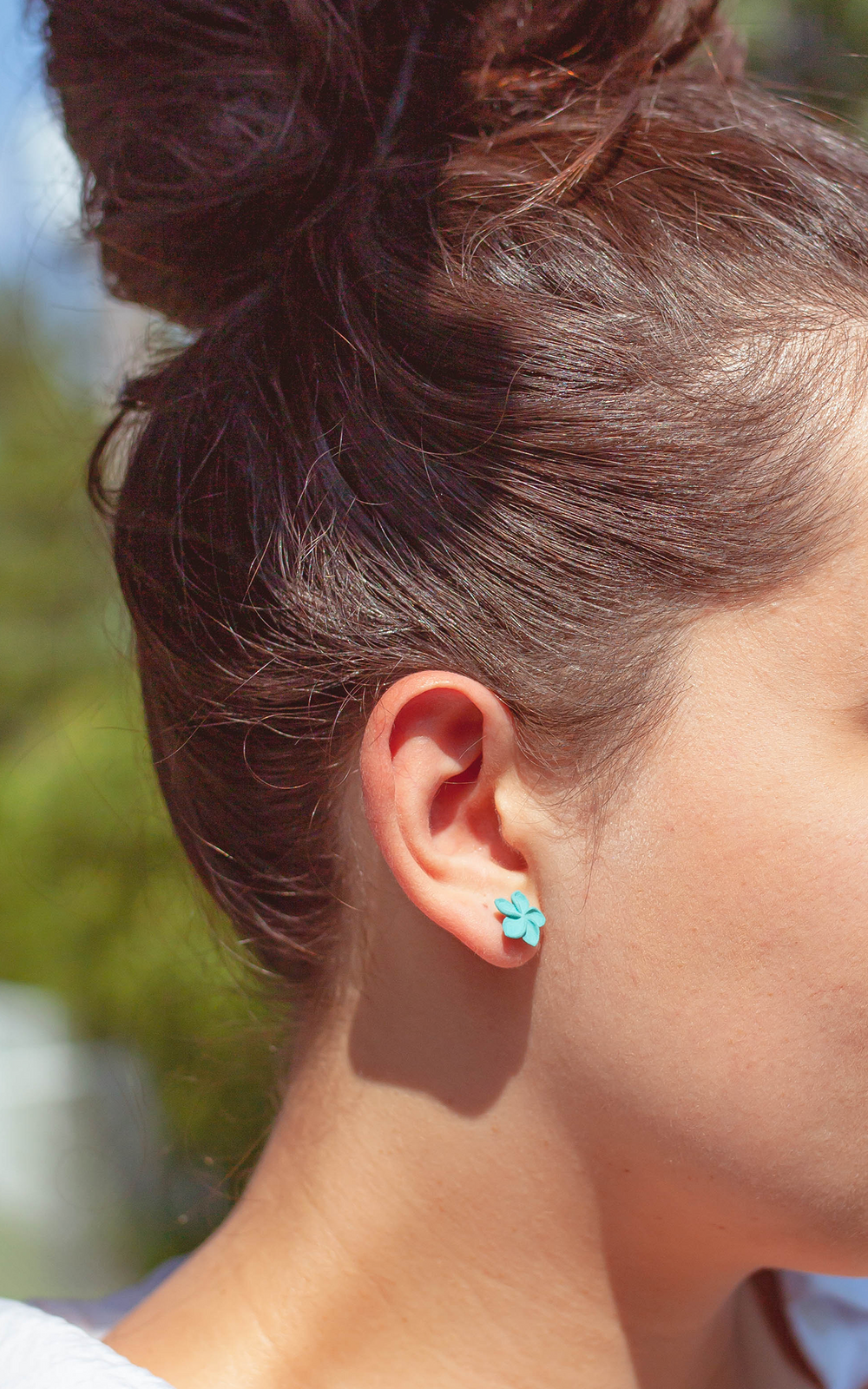 Jeune Femme portant les boucles d’oreilles OHANA, fleur de plumeria blanche en bijou 3D, look tropical et élégant