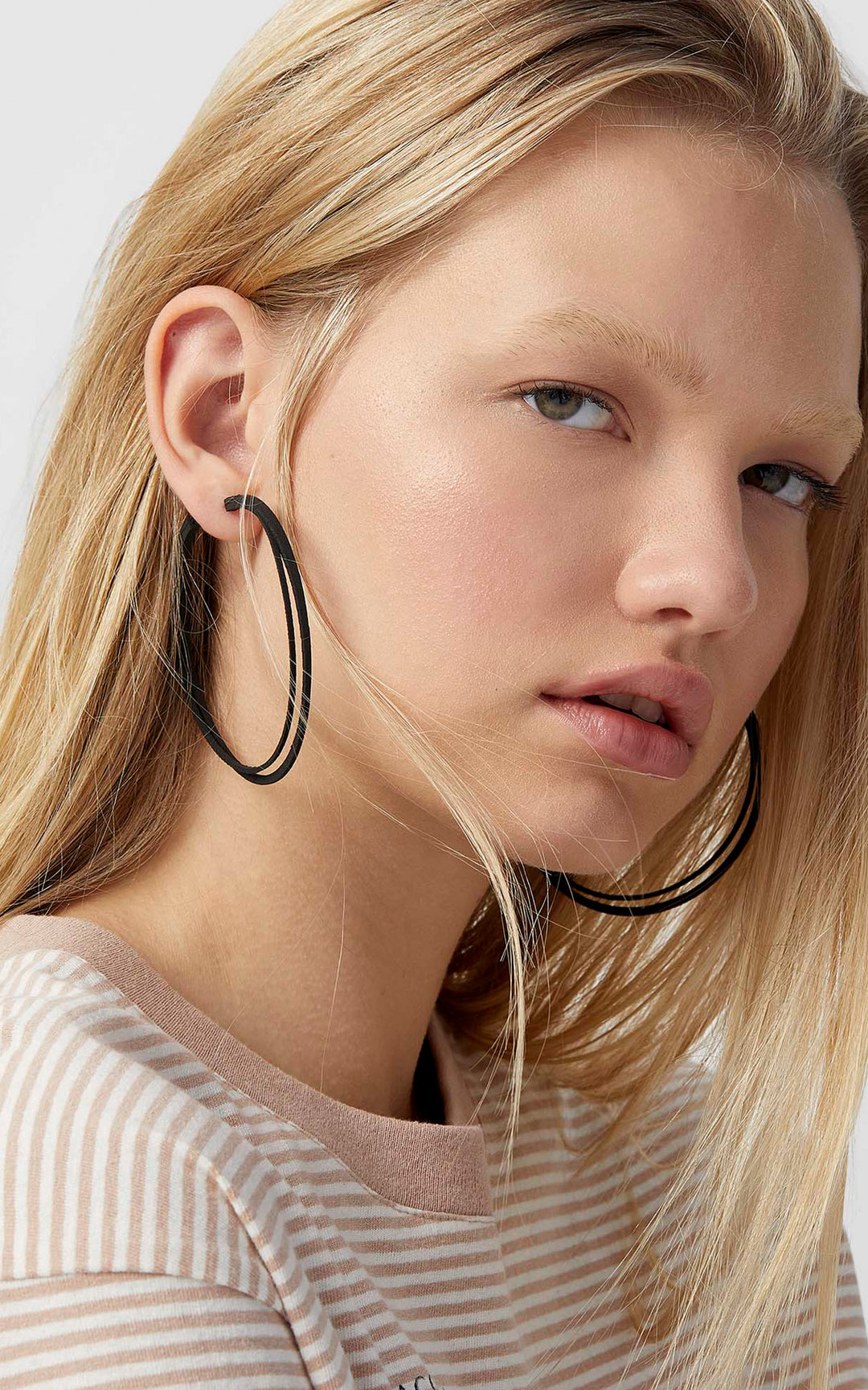 Grands anneaux d'oreilles noirs, Élégante jeune femme blonde portant de jolie boucles d'oreilles noires.